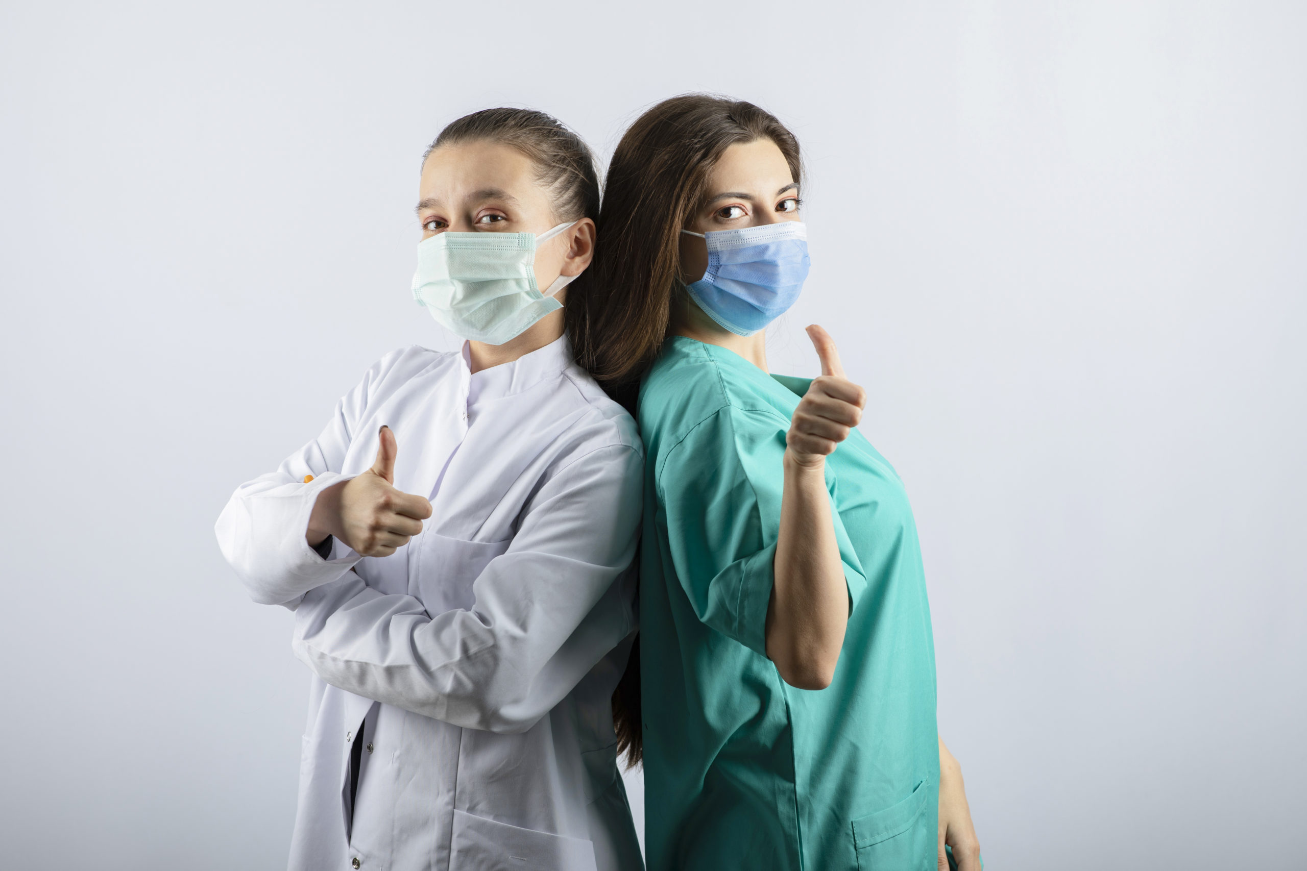Female doctors in medical masks showing thumbs up. High quality photo
